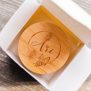 May include: A wooden lid with the name "Ari" engraved on it. The lid has a bee design and is in a white box.