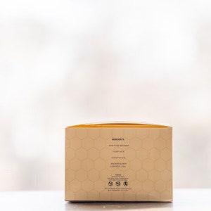 May include: A beige box with a honeycomb pattern and the text "Ingredients: 100% Pure Beeswax, Honey Wax, Coconut Oil, Avocado Oil, Essential Oil" printed on the side.