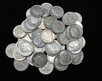 Op de afbeelding: Een stapel zilveren Amerikaanse dimes, elk met een profiel van een man en het woord "Liberty". De munten liggen verspreid op een zwarte achtergrond, met op sommige "One Dime" zichtbaar.