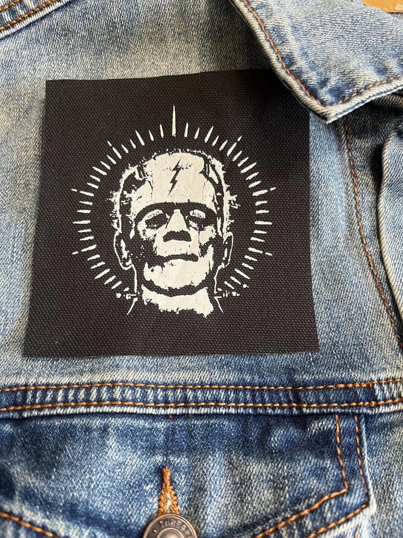 Peut inclure: Patch thermocollant noir avec un motif blanc de Frankenstein avec un &eacute;clair sur le front. Le monstre est entour&eacute; d'un cercle blanc avec des lignes rayonnantes.