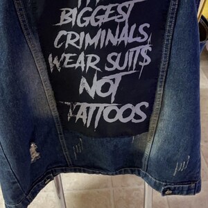 Large punk back patch with bold stencil text 'The Biggest Criminals Wear Suits Not Tattoos', perfect for jackets, vests, and anti-establishment streetwear.
