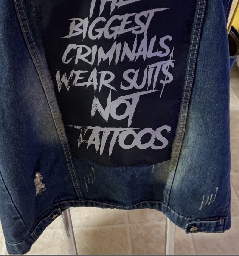 Large punk back patch with bold stencil text 'The Biggest Criminals Wear Suits Not Tattoos', perfect for jackets, vests, and anti-establishment streetwear.