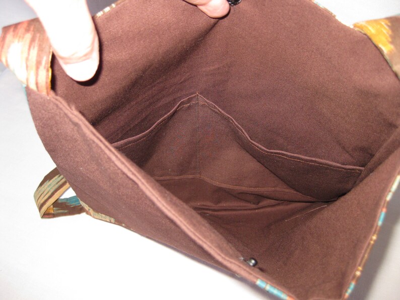 K&ouml;nnte beinhalten: Das Innere einer braunen Stofftasche mit zwei Taschen. Die Tasche hat ein buntes gemustertes Stofffutter.
