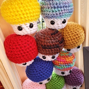 以下が含まれることがあります： 赤、黄、青、緑、紫、茶色、ピンク、黒など、さまざまな色の編みぐるみきのこが積み重ねられています。きのこはピラミッド型に積み重ねられており、一番上が一番大きく、一番下が一番小さいです。