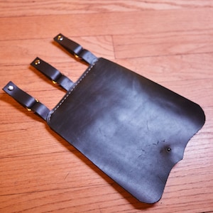 May include: A black leather holster with three straps and silver buckles.