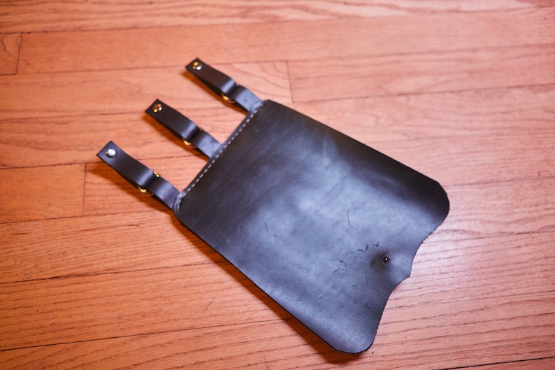 May include: A black leather holster with three straps and silver buckles.