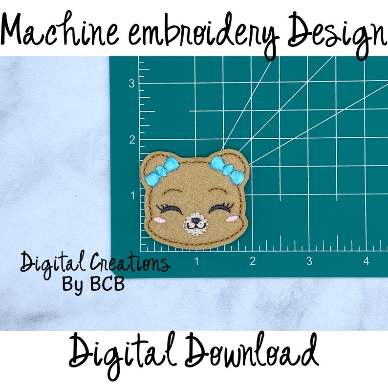 May include: A machine embroidery design featuring a smiling bear face with blue bows, eyelashes, and rosy cheeks. The design is on a green cutting mat with measurements in inches. Text includes "Machine embroidery Design", "Digital Creations By BCB", and "Digital Download".