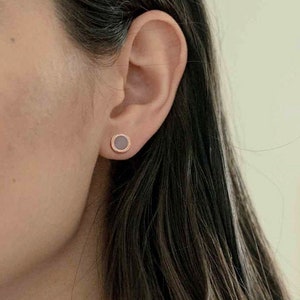 Puede incluir: Un par de pequeños pendientes redondos con un acabado en oro rosa. Los pendientes tienen un diseño circular liso con un brillo sutil.