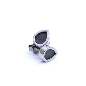 May include: A pair of silver teardrop-shaped earrings with black stones set in the centre.