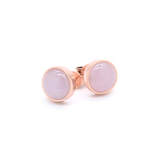 May include: A pair of rose gold stud earrings with pink oval-shaped stones.