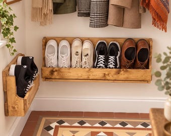 Peut inclure: Deux étagères à chaussures murales en bois avec une finition en grain de bois naturel. La grande étagère horizontale contient quatre paires de baskets et une paire de chaussures en cuir marron. La petite étagère verticale contient une paire de baskets.