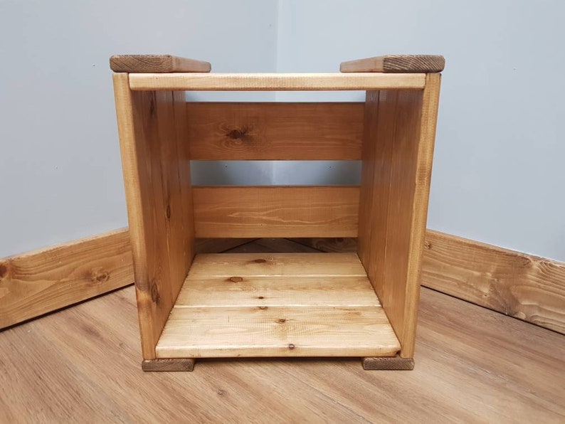 May include: A wooden storage cube with two shelves. The cube is made of natural wood and has a light brown finish.