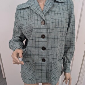 May include: A vintage teal blazer with a plaid pattern. The blazer has a collared neckline, long sleeves, and four dark brown buttons down the front. Two square pockets are on the front. The fabric has a subtle texture.