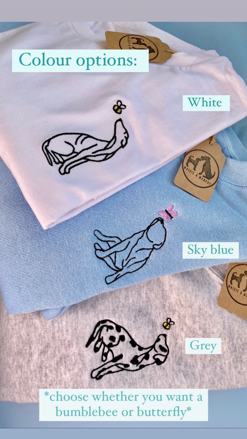 May include: White, sky blue, and grey sweatshirts with embroidered dog designs. Each sweatshirt features a different design: a dog reaching for a bumblebee or butterfly. The text "Colour options" and "choose whether you want a bumblebee or butterfly" are also visible.