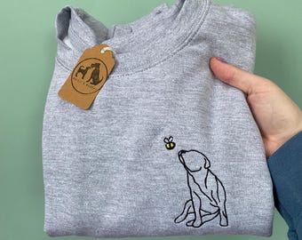 May include: A gray sweatshirt with a black embroidered image of a dog looking up at a bee. The bee is yellow with black stripes. The sweatshirt has a brown tag with the text "Westie & Murphy" on it.