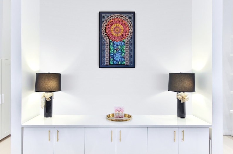 May include: A white cabinet with two doors and gold handles. The cabinet is decorated with two black lamps with black lampshades and a tray with a pink box on top. A framed artwork with a colourful mandala design hangs on the wall above the cabinet.