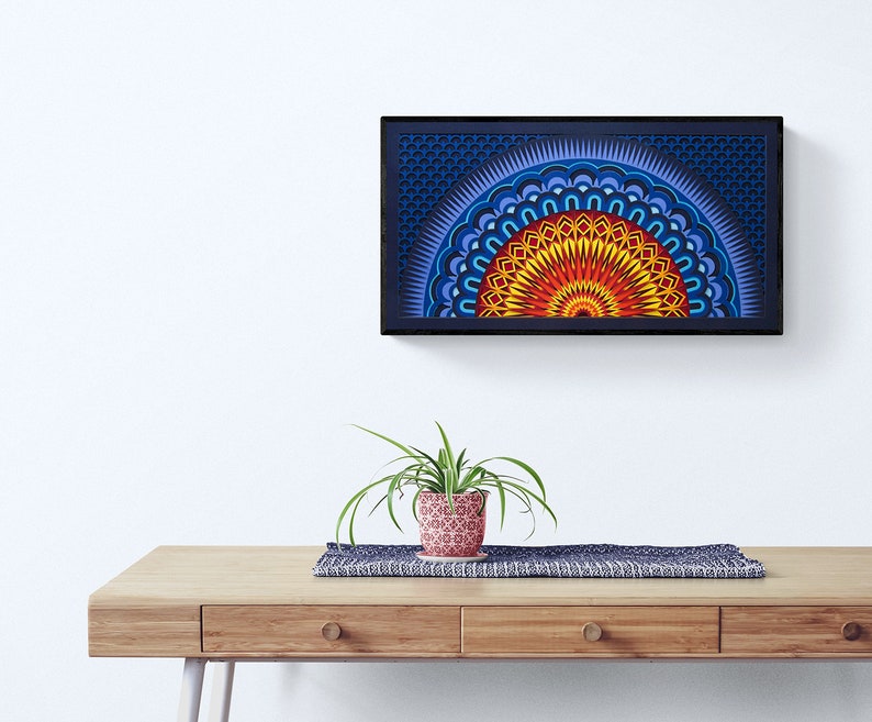 Op de afbeelding: Een rechthoekig wandkunstwerk met een gelaagd, halfrond mandala-ontwerp in levendige tinten geel, oranje, rood en blauw, geplaatst in een zwarte lijst. Het kunstwerk toont ingewikkelde geometrische patronen en concentrische ringen.
