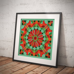 May include: A framed print of a colorful geometric design with red, green, and orange colors. The design is symmetrical and features a starburst pattern in the center.