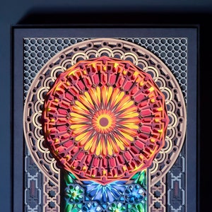 May include: A colourful paper art piece with a red, yellow and orange mandala design. The mandala is surrounded by a geometric pattern in shades of brown and grey.