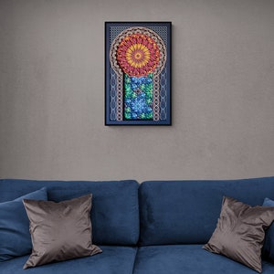 May include: A blue sofa with two brown throw pillows and a framed artwork with a colourful mandala design hanging on the wall behind it.