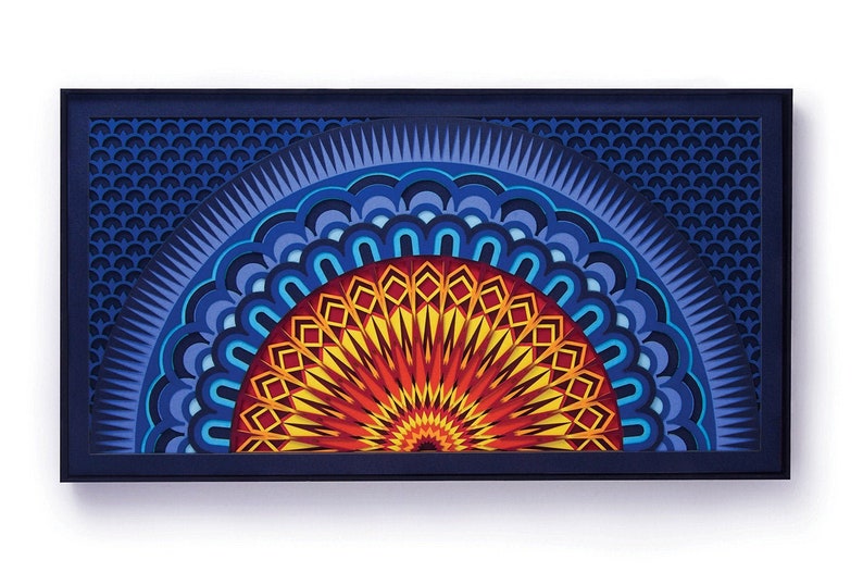 May include: A framed paper art piece featuring a blue, red and yellow mandala design. The mandala is a semi-circle with intricate patterns and layers.
