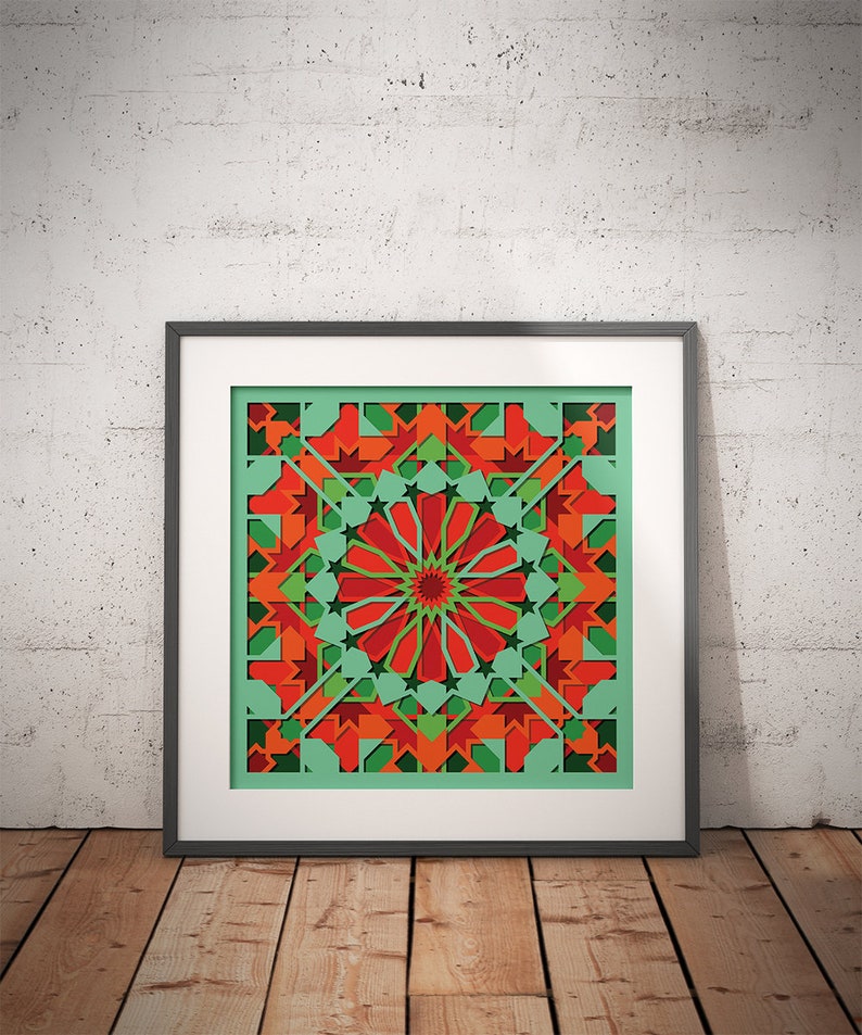 May include: A framed print of a geometric design with red, green, and orange colors. The design is symmetrical and features a central circle with radiating lines.