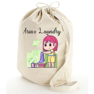 May include: A beige canvas laundry bag with a drawstring closure. The bag features a cartoon illustration of a girl doing laundry with the text "Aria's Laundry" printed on the front.