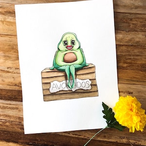 Cute Anxiety Avocado sits on a box of Avocados as a Watercolor Art Print