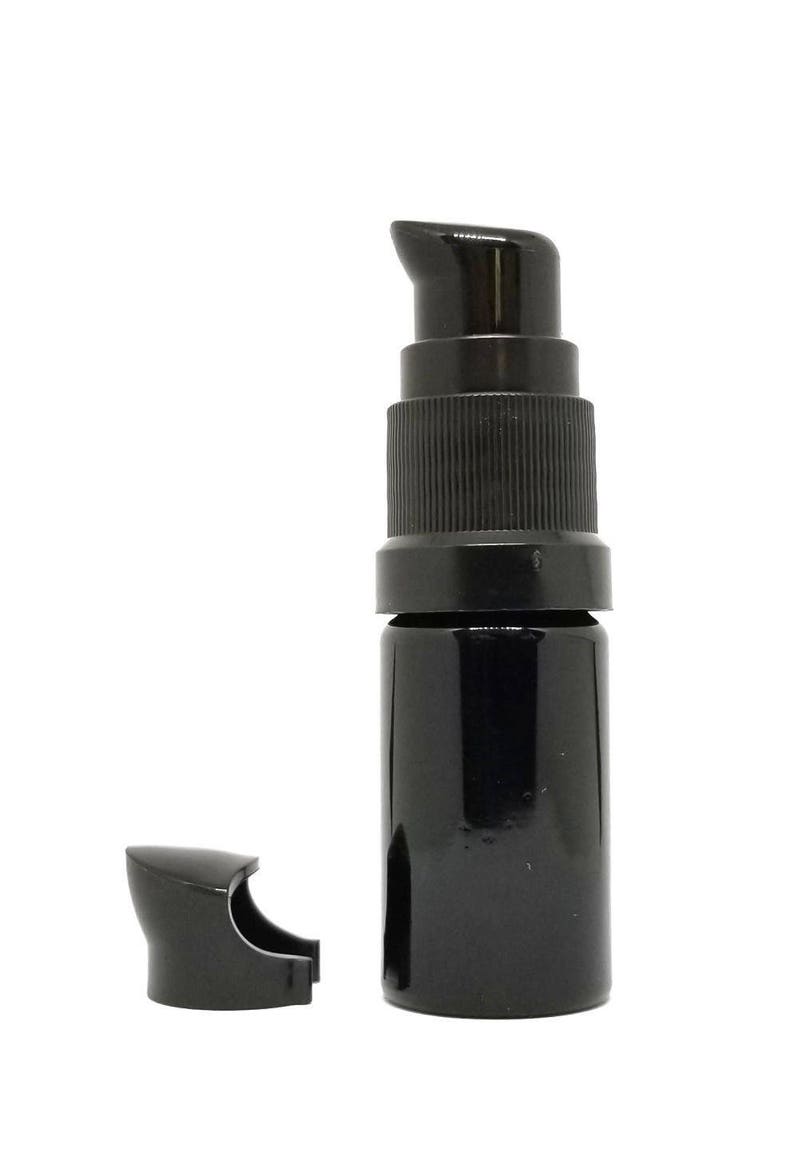 May include: A black glass bottle with a black pump top and a separate black cap. The bottle is about 5 inches tall.