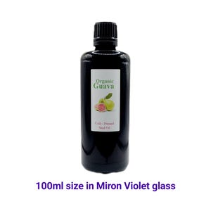 May include: A 100 ml bottle of organic guava seed oil in a dark violet glass bottle. The bottle has a black cap and a label that says "Organic Guava Cold-Pressed Seed Oil".