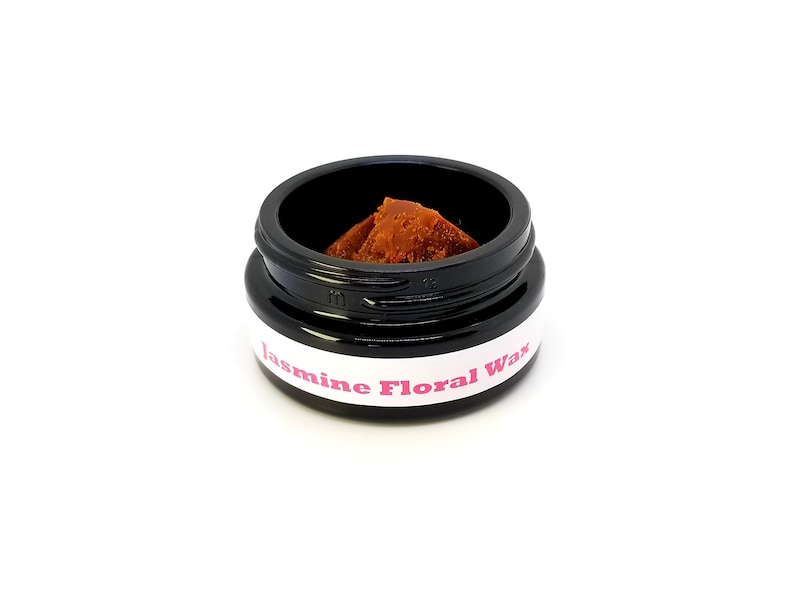 May include: A small black jar with a white label that reads "Jasmine Floral Wax". The jar contains a brown wax melt.
