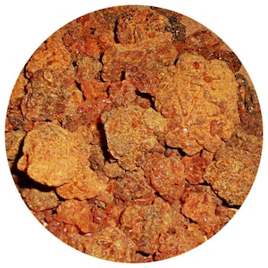 May include: Close-up of a pile of brown and orange resin pieces. The resin is irregularly shaped and has a rough texture.