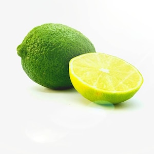 May include: A whole lime and a lime cut in half, both with a green skin and a yellow interior, on a white background.