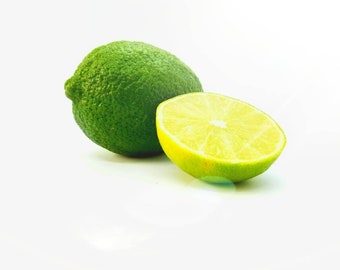 May include: A whole lime and a lime cut in half, both with a green skin and a yellow interior, on a white background.