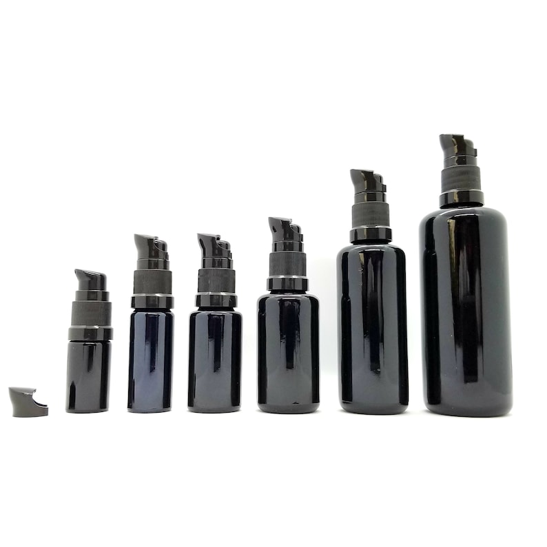 May include: A set of six black glass bottles with black pump tops. The bottles are arranged in order of size, with the largest bottle on the right and the smallest bottle on the left.
