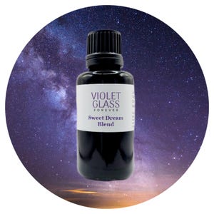 Könnte beinhalten: Eine dunkle Glasflasche mit schwarzem Verschluss und einem weißen Etikett mit der Aufschrift "Violet Glass Forever Sweet Dream Blend". Die Flasche steht auf einem violetten Hintergrund mit weißen Sternen.