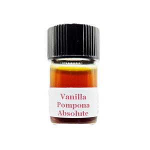 May include: A small glass bottle with a black cap, containing a dark amber liquid. A white label with red text reads "Vanilla Pompona Absolute". The bottle is set against a white background.