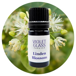 Peut inclure: Petite bouteille en verre foncé avec un bouchon noir, étiquetée "Violet Glass Forever" et "Linden Blossom". L'arrière-plan est composé de fleurs de tilleul blanches et jaunes, créant un thème naturel et botanique.