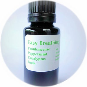 May include: A small dark brown glass bottle with a black cap and a white label that reads "Easy Breathing" with the ingredients "Frankincense, Peppermint, Eucalyptus, Inula" listed below.