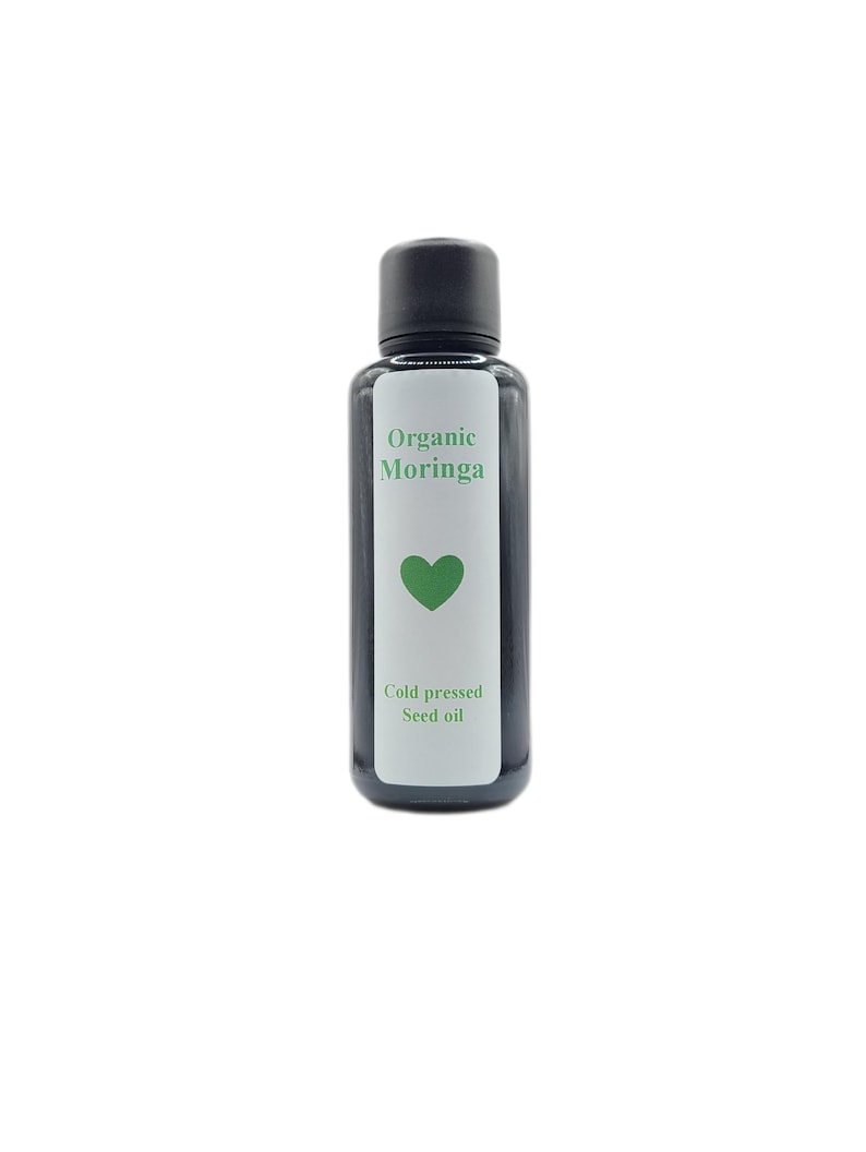 Pode incluir: Uma garrafa preta com um r&oacute;tulo branco que diz "Organic Moringa Cold pressed Seed oil" com um &iacute;cone de cora&ccedil;&atilde;o verde.