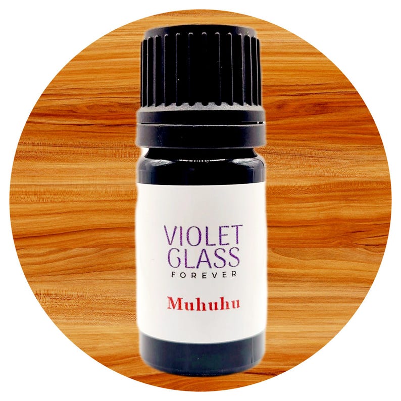 Pode incluir: Um pequeno frasco de vidro castanho escuro com uma tampa preta. O frasco &eacute; etiquetado com "Violet Glass Forever" e "Mukuhu" em texto branco.