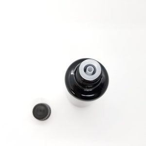 May include: A black glass bottle with a white dropper top and a black screw-on cap. The bottle is empty and the dropper is in the open position.
