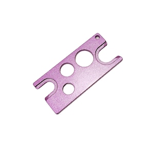 Può includere: Un multiutensile in metallo rosa con un apribottiglie, un aprilattine e tre fori di diverse dimensioni per aprire i pacchetti.