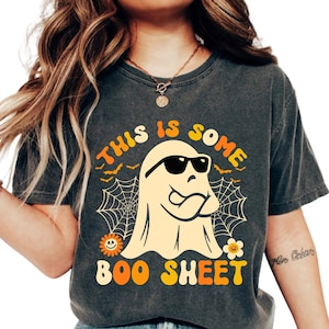 May include: A dark gray t-shirt with a retro-style ghost wearing sunglasses and the text "This is some boo sheet".