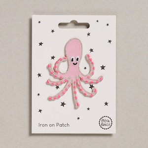 Pode incluir: Etiqueta de ferro rosa com um polvo sorridente com detalhes em rosa e branco. A etiqueta está em um cartão branco com estrelas pretas e o texto "Iron on Patch".