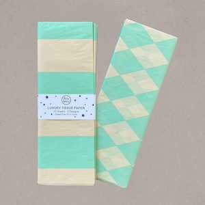 May include: Two stacks of luxury tissue paper. One stack is banded with a label that reads "Luxury Tissue Paper". The tissue paper has alternating stripes of mint green and cream. The other tissue paper has a diamond pattern in mint green and cream.