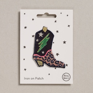 May include: Iron-on patch featuring a black cowboy boot with a green lightning bolt, pink and leopard print accents, and gold stars. The patch is on a white card with the text "Iron on Patch" and a small logo that says "Petra Boase".