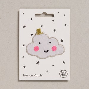 May include: Iron-on patch featuring a white cloud with a pink smile, rosy cheeks, and a gold top hat. The patch is on a white card with black stars and the text "Iron on Patch".