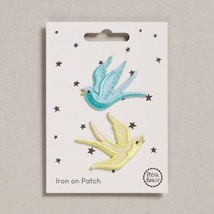 May include: Two iron-on patches featuring a blue and a yellow bird design. The patches are on a white card with black stars and the text "Iron on Patch" and "Petra Boase".