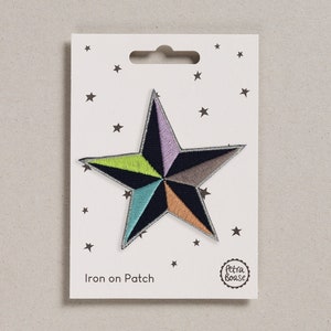 May include: Iron-on patch featuring a colourful star with a navy blue background. The star has a geometric design with shades of green, purple, orange, and grey. The patch is packaged on a white card with the text "Iron on Patch" and the Petra Boase logo.